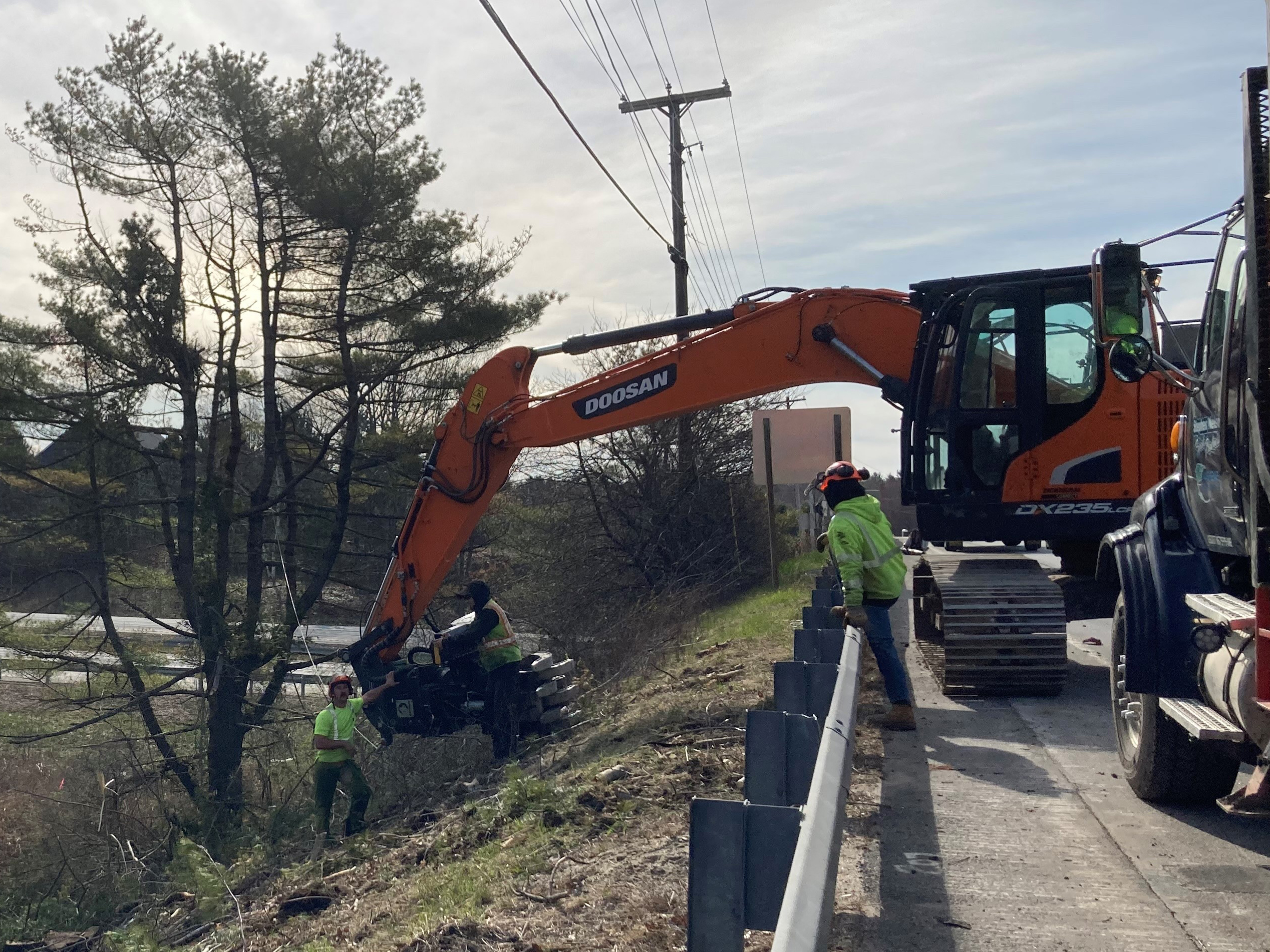 Workers oversee continued site cleaning as machines work from nearby bridge